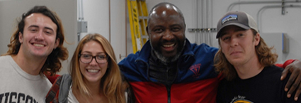 Dr. Folarin Oguntoyinbo poses with three students.