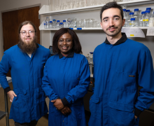 From left, Jackson Johnson, Dr. Nancy Asen, and Jack Kelly in the lab. Photo by Chase Reynolds Three individuals wearing blue jackets in a scientific lab.