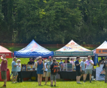Tents with people drinking beer in front of them.